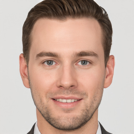 Joyful white young-adult male with short  brown hair and grey eyes