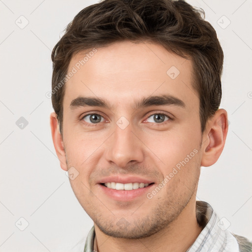 Joyful white young-adult male with short  brown hair and grey eyes