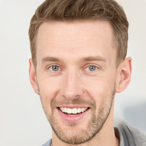 Joyful white young-adult male with short  brown hair and grey eyes