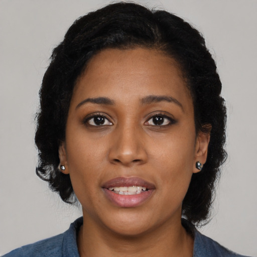 Joyful black young-adult female with long  black hair and brown eyes