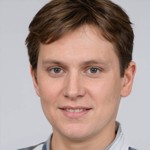 Joyful white young-adult male with short  brown hair and grey eyes