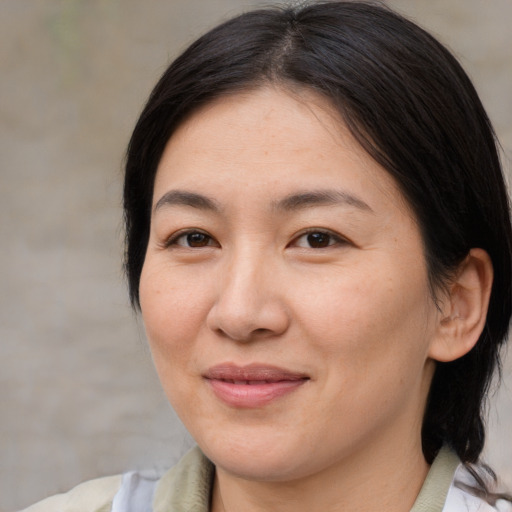 Joyful asian adult female with medium  brown hair and brown eyes