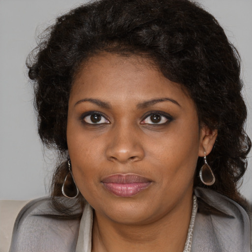Joyful black young-adult female with long  brown hair and brown eyes