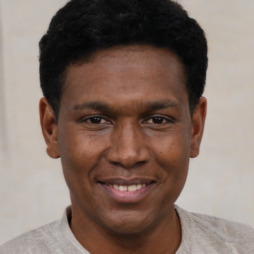 Joyful black young-adult male with short  black hair and brown eyes