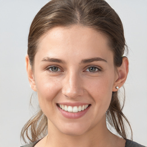 Joyful white young-adult female with medium  brown hair and grey eyes