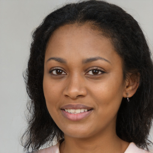 Joyful black young-adult female with long  brown hair and brown eyes