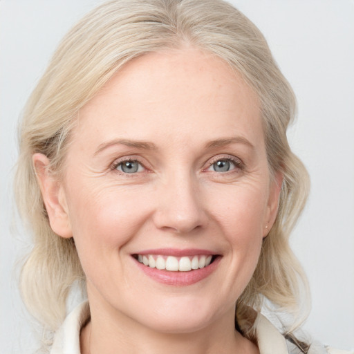 Joyful white adult female with medium  blond hair and blue eyes