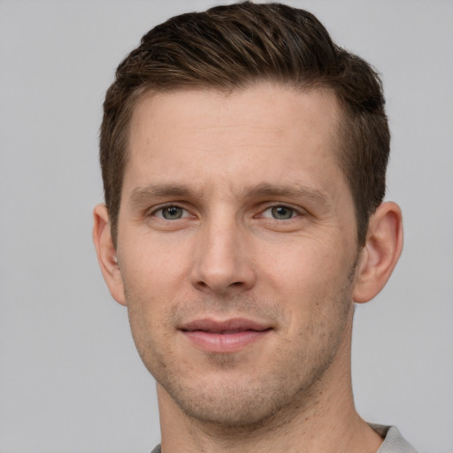 Joyful white young-adult male with short  brown hair and grey eyes