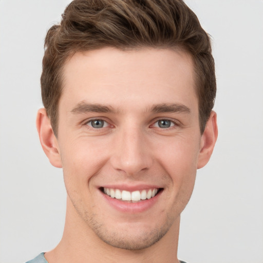 Joyful white young-adult male with short  brown hair and grey eyes