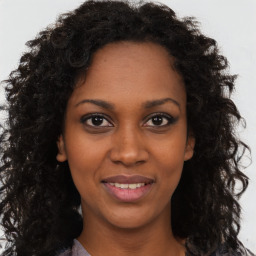 Joyful black young-adult female with long  brown hair and brown eyes