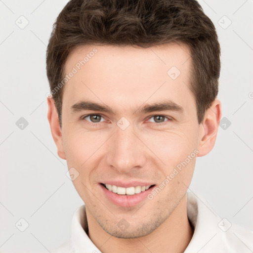 Joyful white young-adult male with short  brown hair and grey eyes