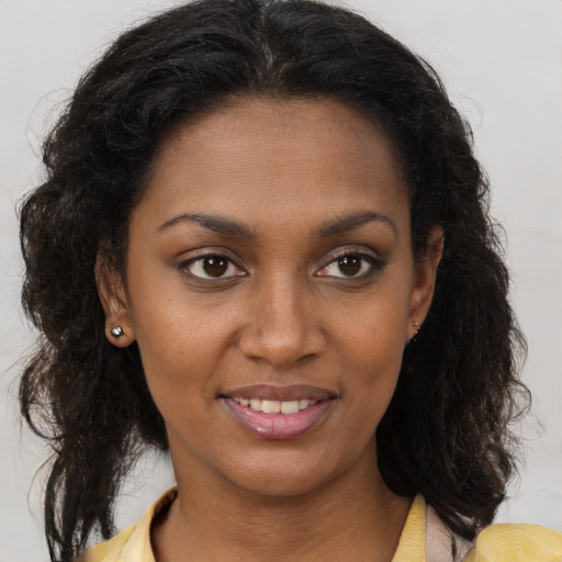 Joyful black young-adult female with long  brown hair and brown eyes