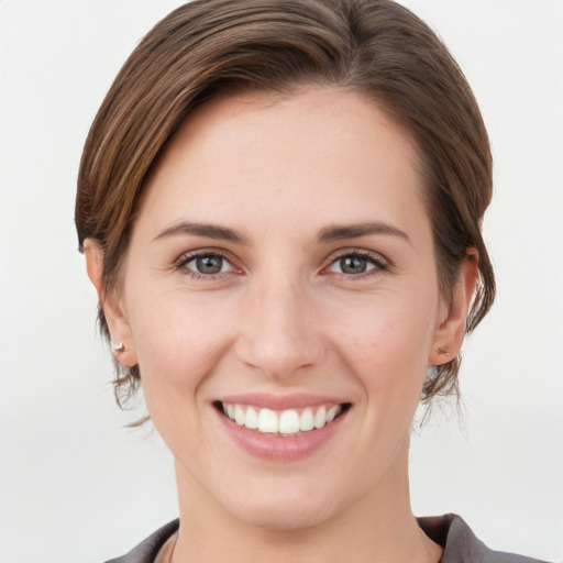 Joyful white young-adult female with medium  brown hair and grey eyes