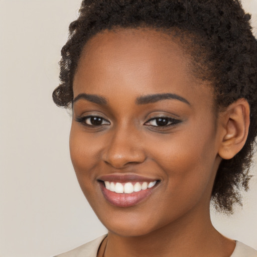 Joyful black young-adult female with long  brown hair and brown eyes