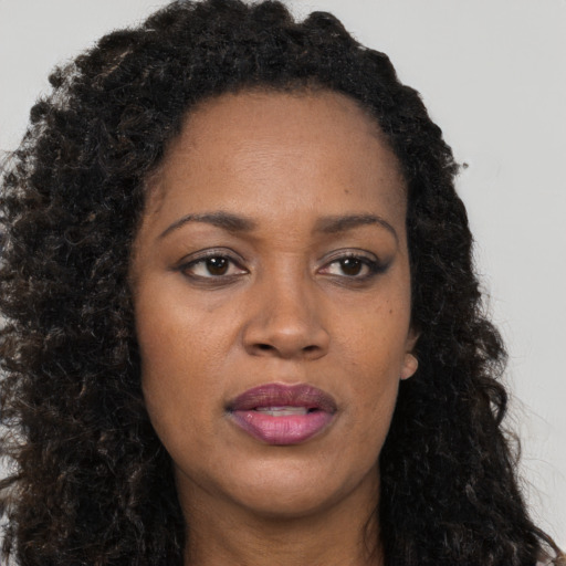 Joyful black adult female with long  brown hair and brown eyes