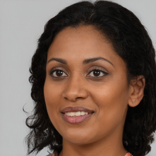 Joyful black young-adult female with long  brown hair and brown eyes