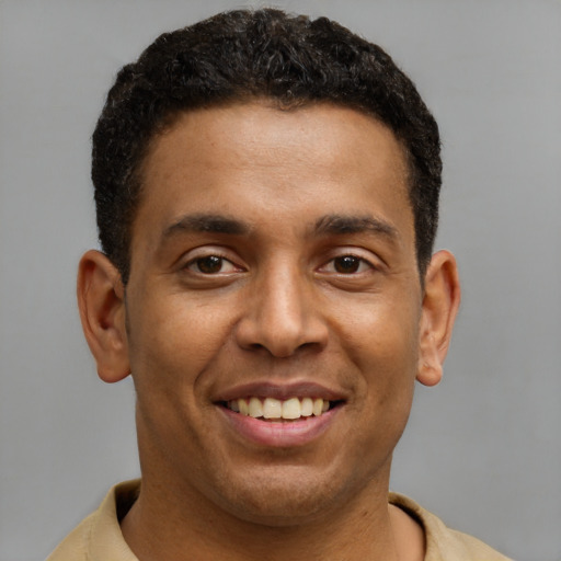 Joyful black young-adult male with short  brown hair and brown eyes