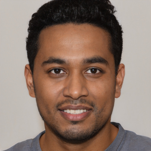 Joyful black young-adult male with short  black hair and brown eyes