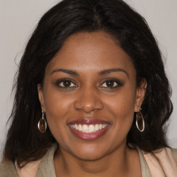 Joyful black young-adult female with long  brown hair and brown eyes