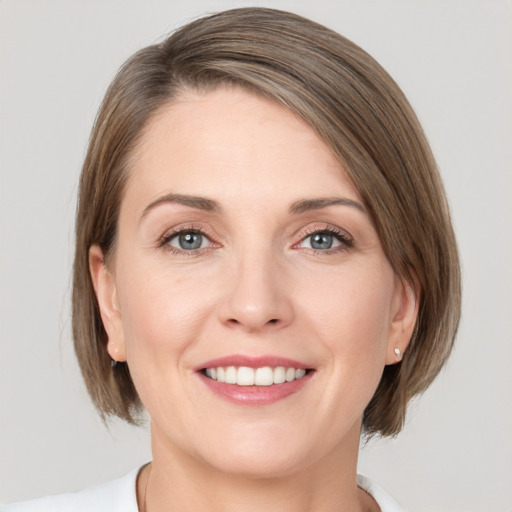 Joyful white young-adult female with medium  brown hair and grey eyes