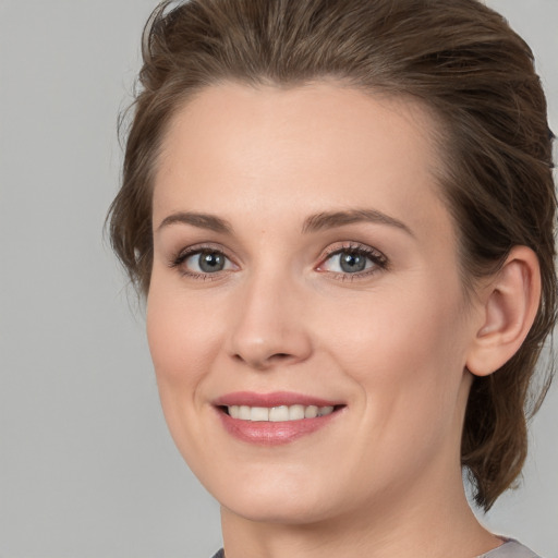 Joyful white young-adult female with medium  brown hair and grey eyes