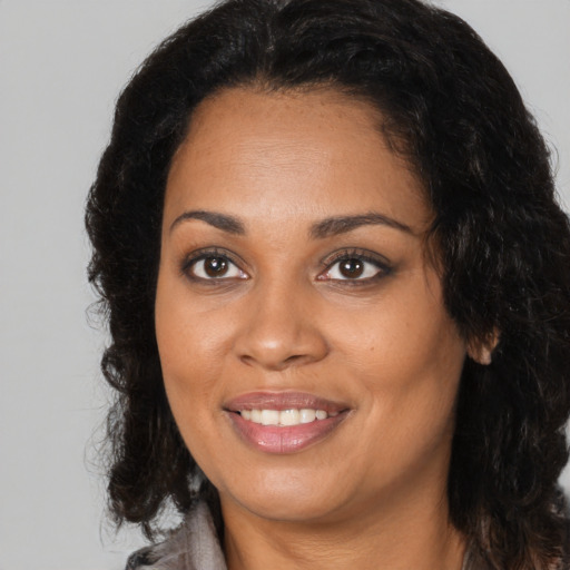 Joyful black young-adult female with long  brown hair and brown eyes