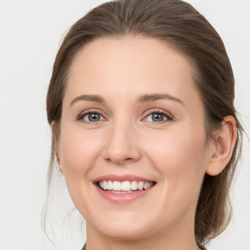 Joyful white young-adult female with medium  brown hair and grey eyes