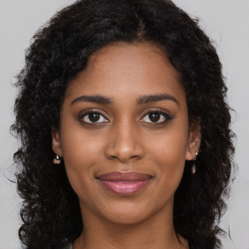 Joyful black young-adult female with long  black hair and brown eyes