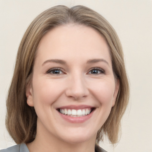 Joyful white young-adult female with medium  brown hair and grey eyes