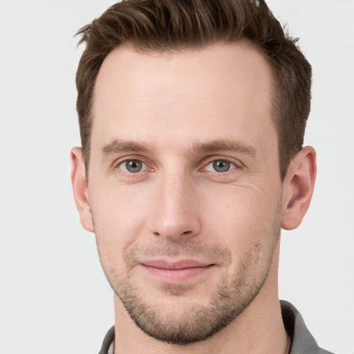 Joyful white young-adult male with short  brown hair and grey eyes