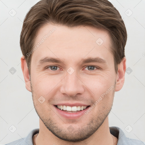 Joyful white young-adult male with short  brown hair and grey eyes