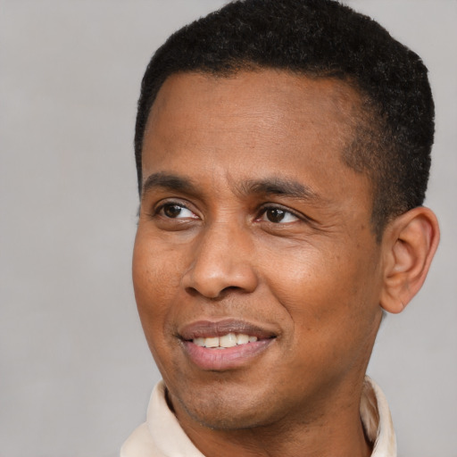 Joyful black adult male with short  black hair and brown eyes