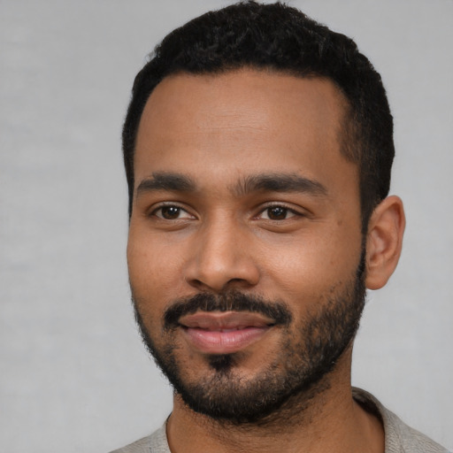 Joyful black young-adult male with short  black hair and brown eyes