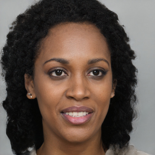 Joyful black young-adult female with long  brown hair and brown eyes