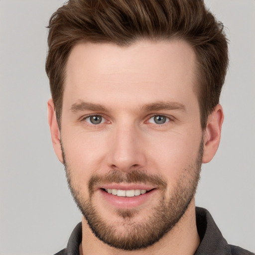 Joyful white young-adult male with short  brown hair and grey eyes