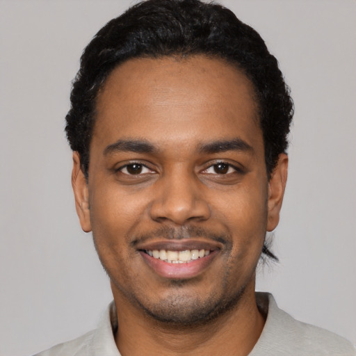 Joyful black young-adult male with short  black hair and brown eyes