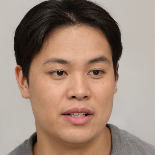 Joyful asian young-adult male with short  brown hair and brown eyes