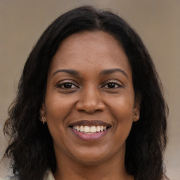 Joyful black young-adult female with long  brown hair and brown eyes