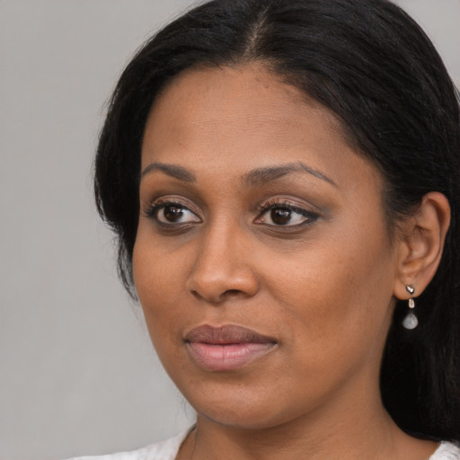 Joyful black young-adult female with long  black hair and brown eyes