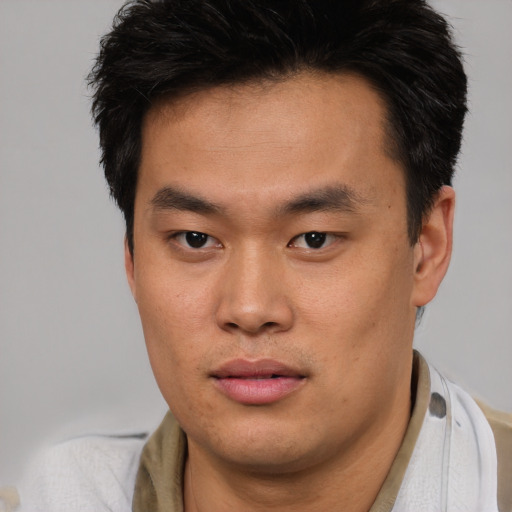 Joyful asian young-adult male with short  brown hair and brown eyes