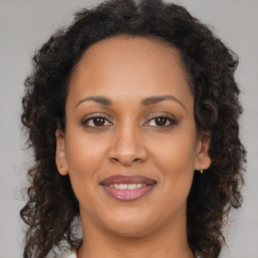 Joyful black young-adult female with long  brown hair and brown eyes