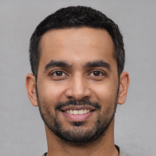 Joyful latino young-adult male with short  black hair and brown eyes