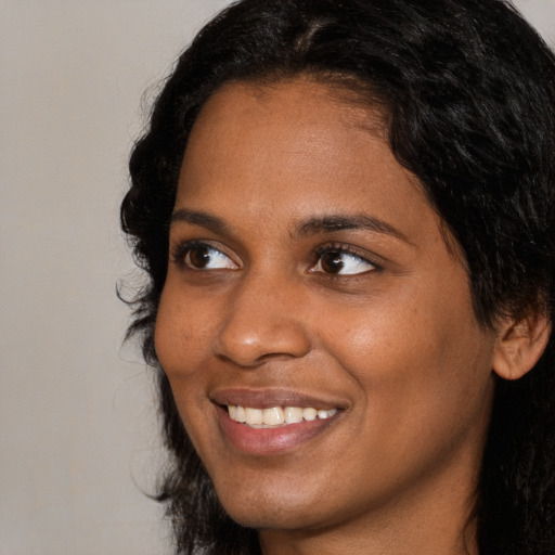 Joyful black young-adult female with long  brown hair and brown eyes