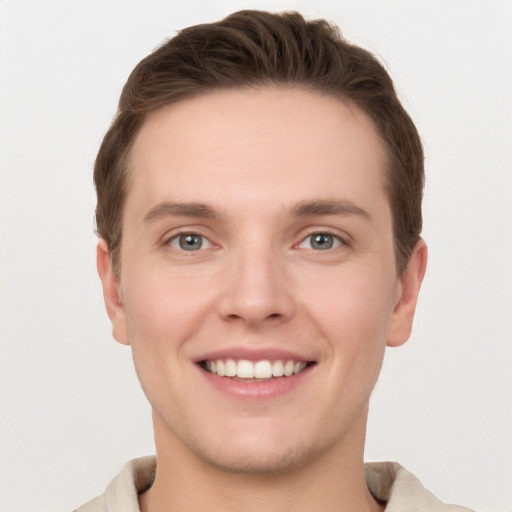 Joyful white young-adult male with short  brown hair and grey eyes