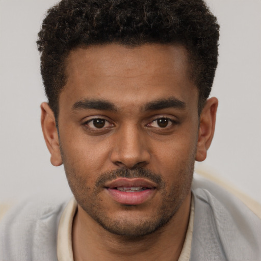 Joyful black young-adult male with short  brown hair and brown eyes