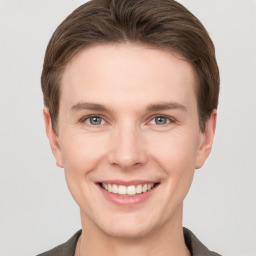 Joyful white young-adult male with short  brown hair and grey eyes