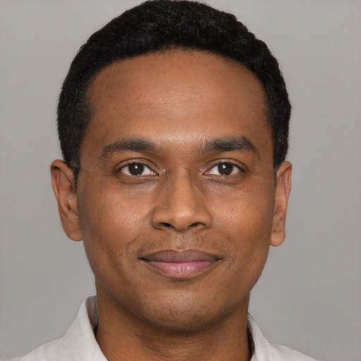 Joyful black young-adult male with short  black hair and brown eyes