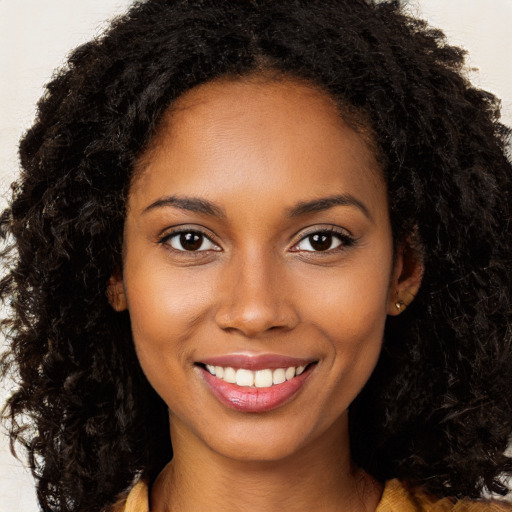 Joyful black young-adult female with long  brown hair and brown eyes