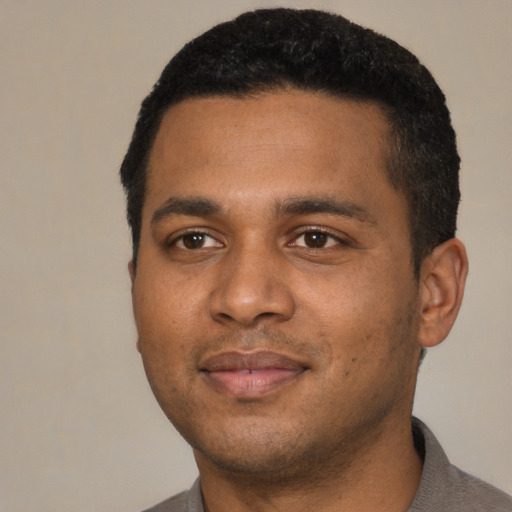 Joyful black young-adult male with short  black hair and brown eyes