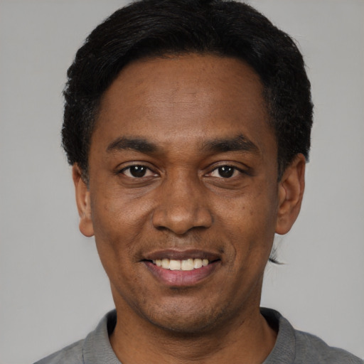 Joyful black adult male with short  black hair and brown eyes